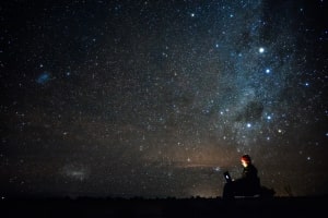 Image of Man typing outside under the stars. Link to Blog